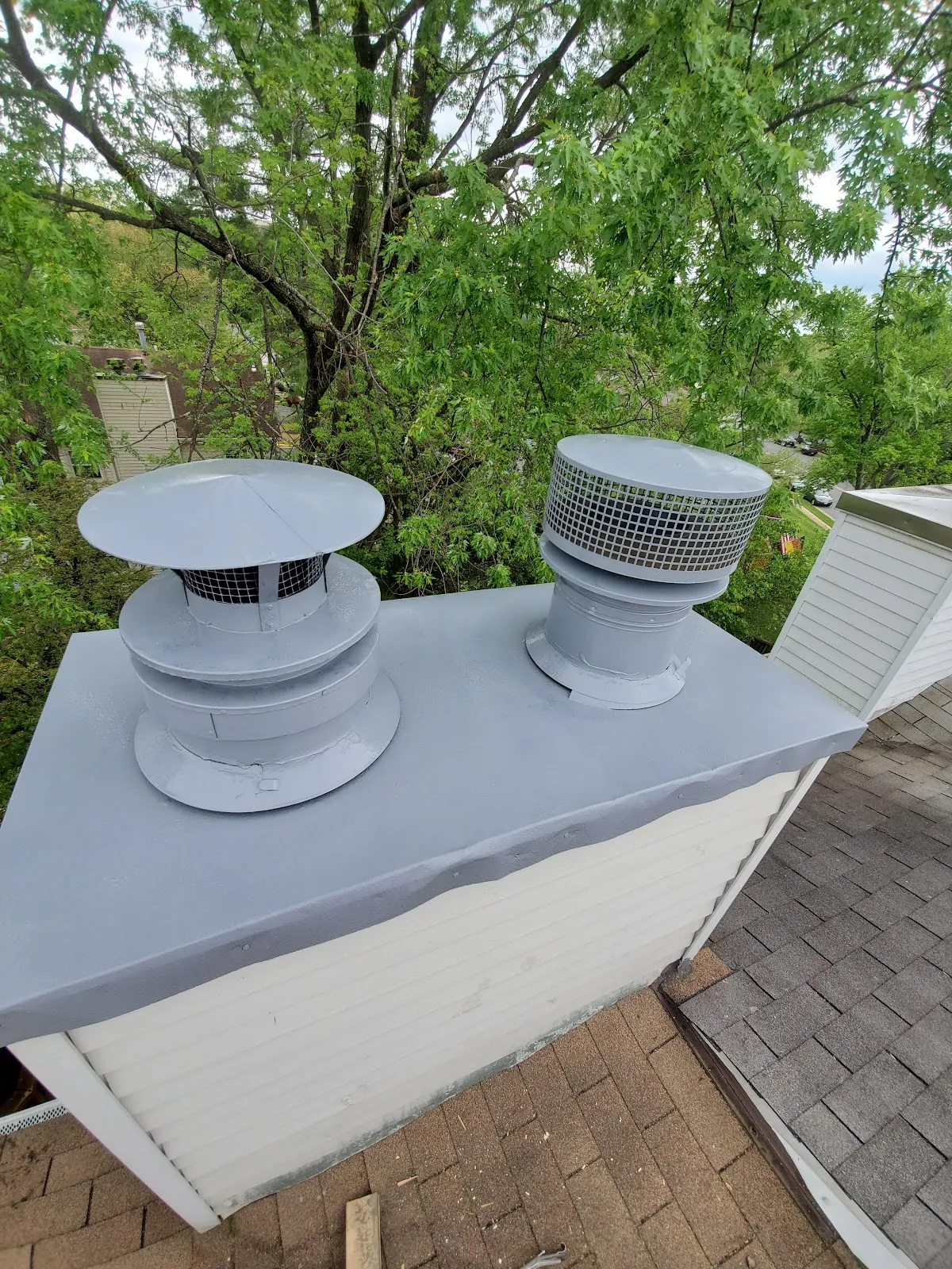 Two grey chimney caps freshly painted and sealed on a chimney chase