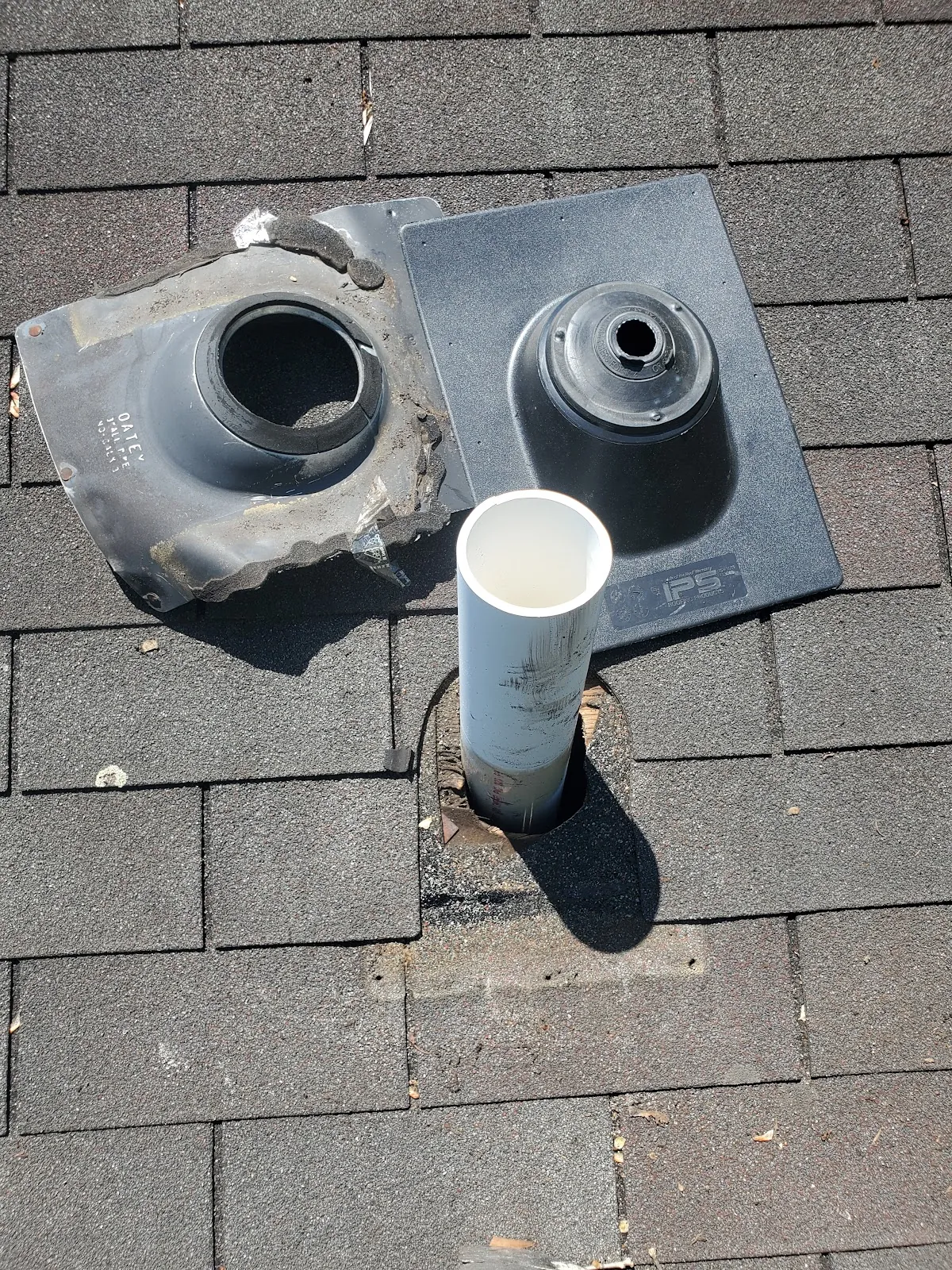 Cracked old roof pipe boot beside its replacement on an asphalt shingle roof