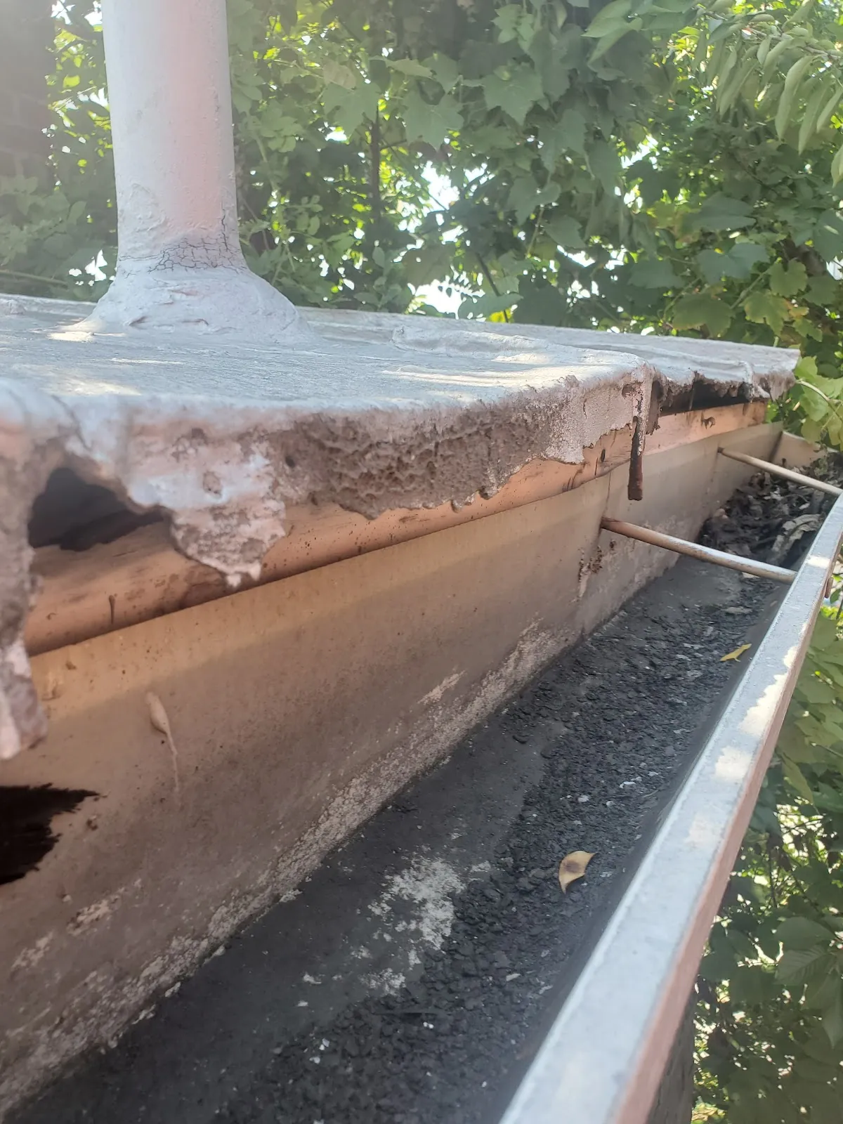 Close-up of a failed, spalling chimney crown found above a gutter line