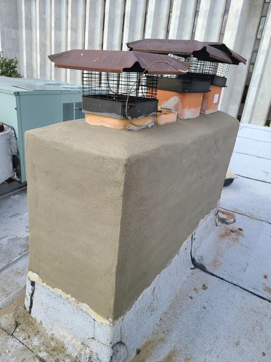 Rebuilt chimney crown with three new screened caps on a flat roof